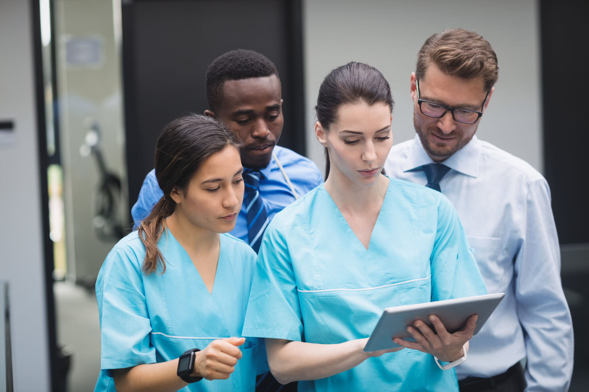 Medical team discussing over digital tablet in hospital corridor